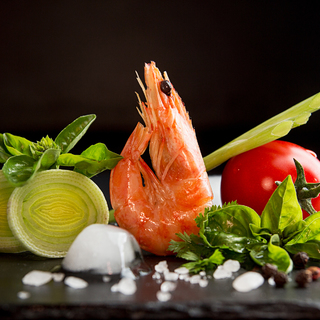 Shrimp prawn serving with leek, basil, ice against black background. Seefood diet concept. Healthy food