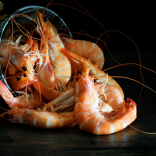 Fresh shrimps in the bucket on the wooden natural background.