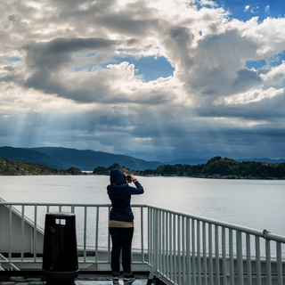 The girl on the deck of the ferry taking pictures of the beautiful Northern landscape.