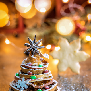 Christmas tree made out of dried orange slices and anise star, with festive light on background, vertical composition