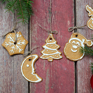 Fir branch with Christmas decorations near a wooden wall with Christmas cookies