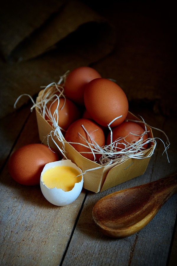 Many village eggs lie in a wicker basket in the chicken coop on the wooden floor.