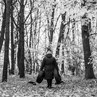 Женщина идет домой и несет с собой старые автомобильные покрышки,чтобы использовать их в хозяйстве и украсить территорию возле ее дома. Могилев,Беларусь