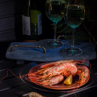 giant shrimp, lemon, two glasses of white wine. Bright photo on a black background
