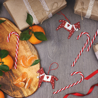 Christmas concept - candy canes, tangerines, horse-shaped decorations and rustic-style gifts