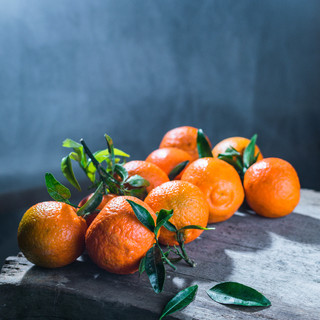 Tangerines oranges, mandarins, clementines, citrus fruits with leaves in basket over rustic wooden background, copy space
