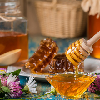 Two honey pots with honeycomb  on a wooden table  with flowers