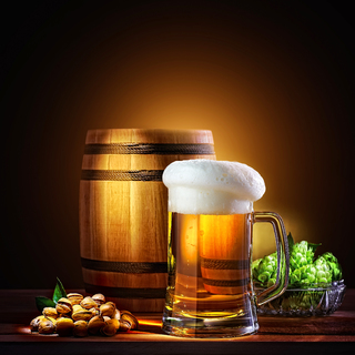 Beer barrel with beer glass on a wooden table. The dark background.