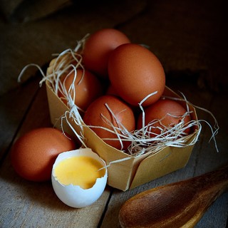 Many village eggs lie in a wicker basket in the chicken coop on the wooden floor.