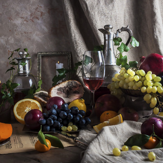 Still life with red wine, fruits, pomegranate, grapes and cheese.