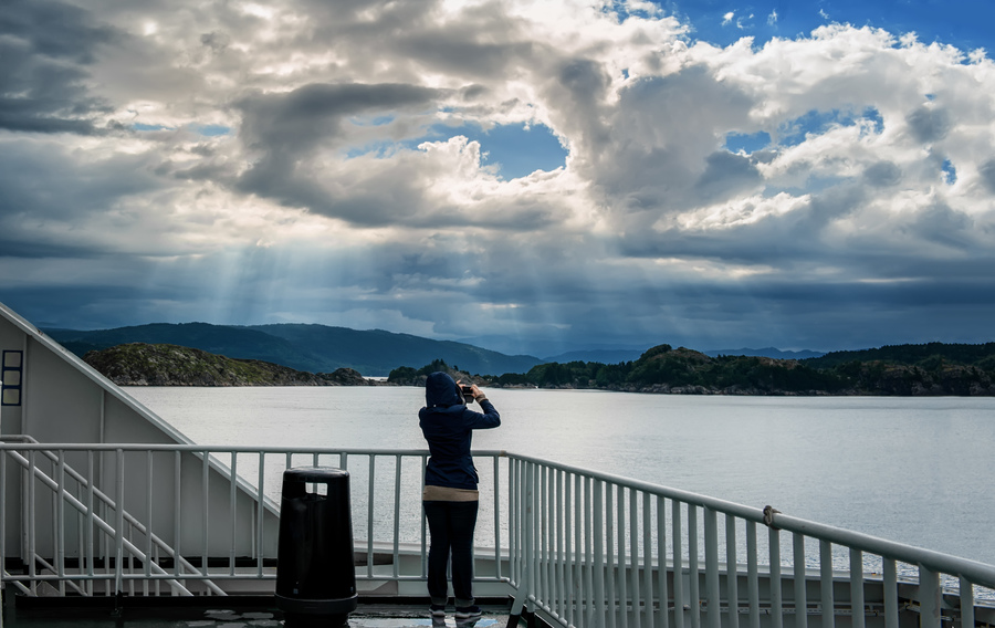 The girl on the deck of the ferry taking pictures of the beautiful Northern landscape.