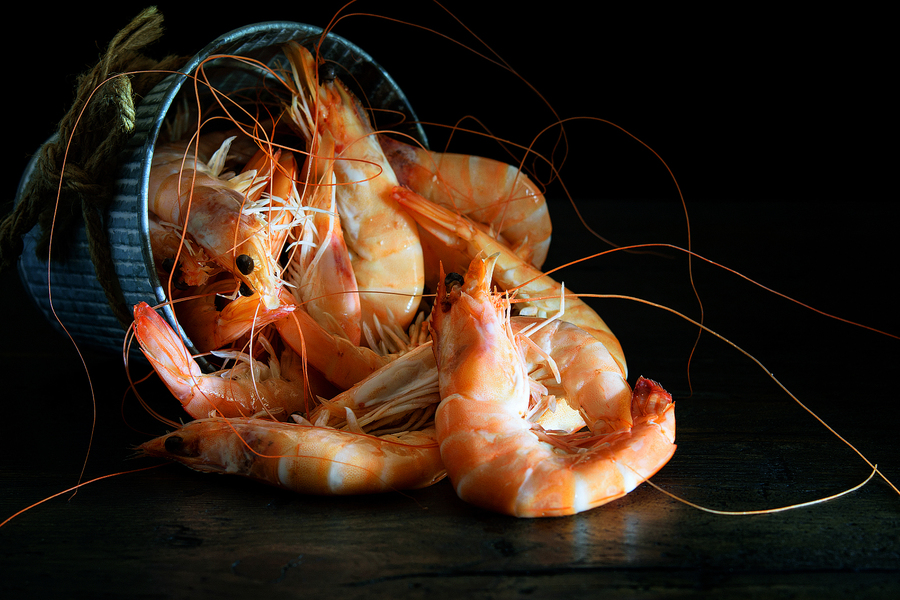 Fresh shrimps in the bucket on the wooden natural background.