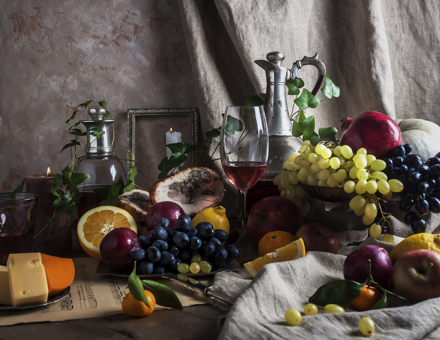 Still life with red wine, fruits, pomegranate, grapes and cheese.