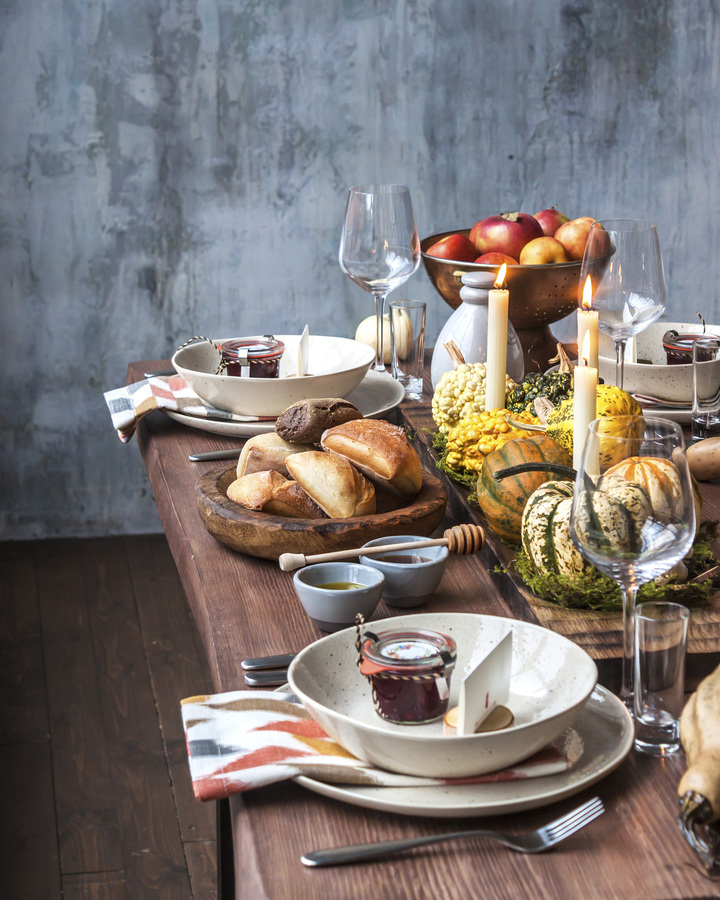 Rustic table setting with pumpkin soup and pumpkins on the background of the window in the loft