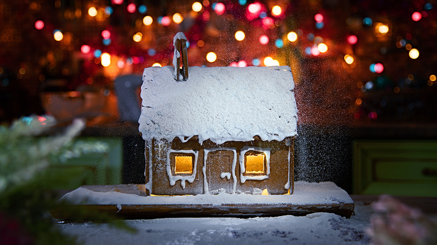 Gingerbread house sprinkled with icing sugar like snow. The spirit of Christmas. Garland on the background
