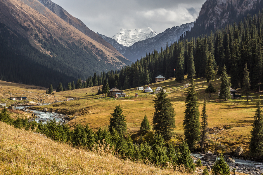 mountain gorge with snowy peaks and yurts in the middle