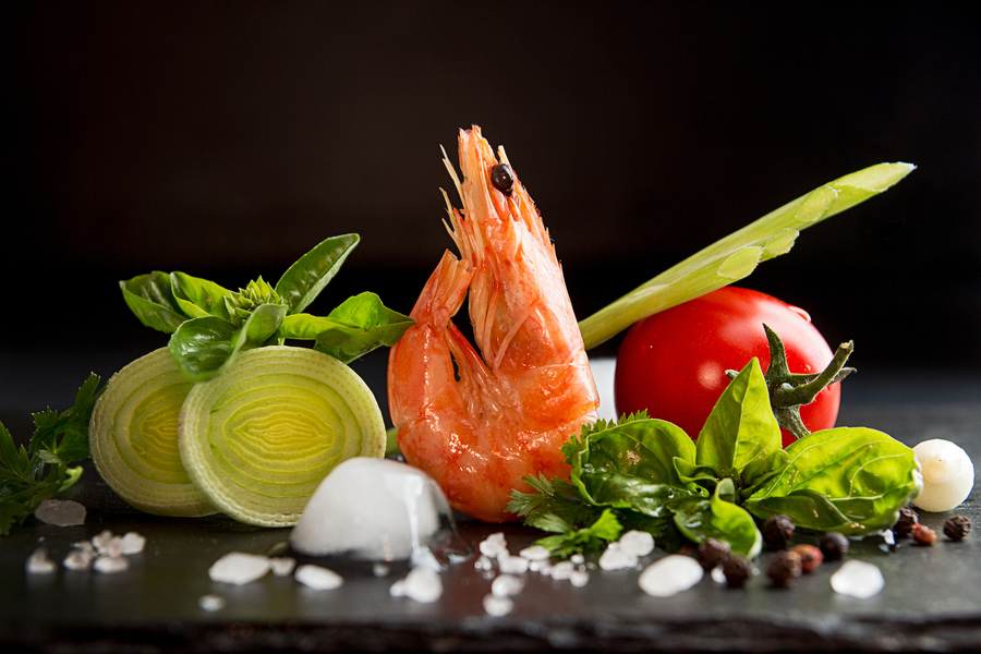 Shrimp prawn serving with leek, basil, ice against black background. Seefood diet concept. Healthy food