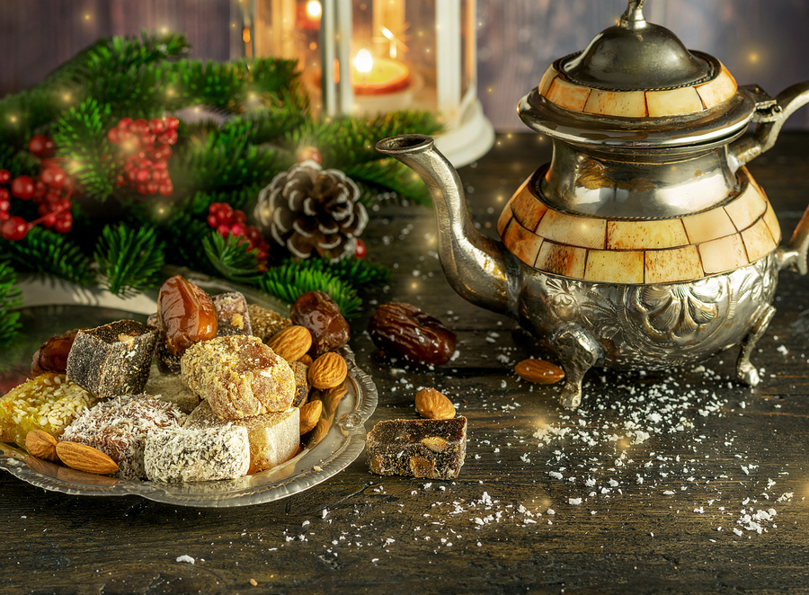 Oriental sweetness Turkish delight and rahat on the metal vintage plate with teapot in winter Christmas decoration on the wooden natural background.